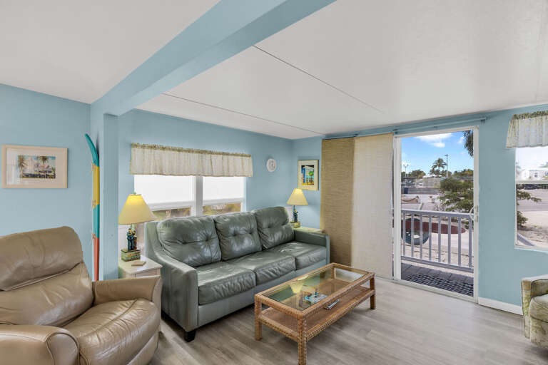 Light-filled Living Space With Blue Beams, Balcony View, And Plush Seating