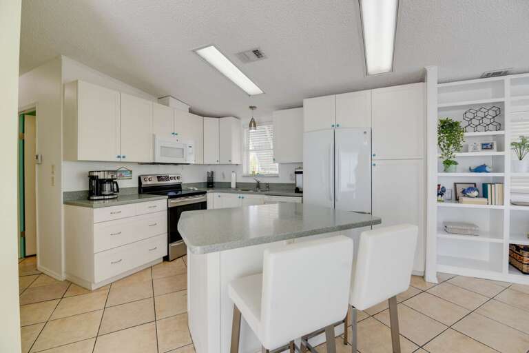 Bright, White Kitchen With Built-in Appliances And Central Island