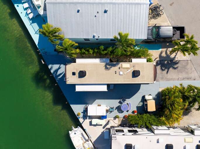 Aerial View Of Seaside Vacation Rental Nestled Between Vibrant Vegetation And Vivid Waters