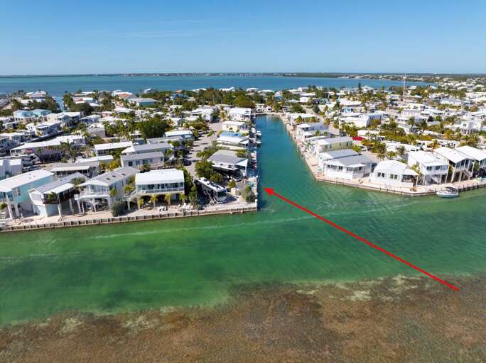 Aerial View Of A Coastal Community With Clustered Buildings Beside A Clear Blue Canal