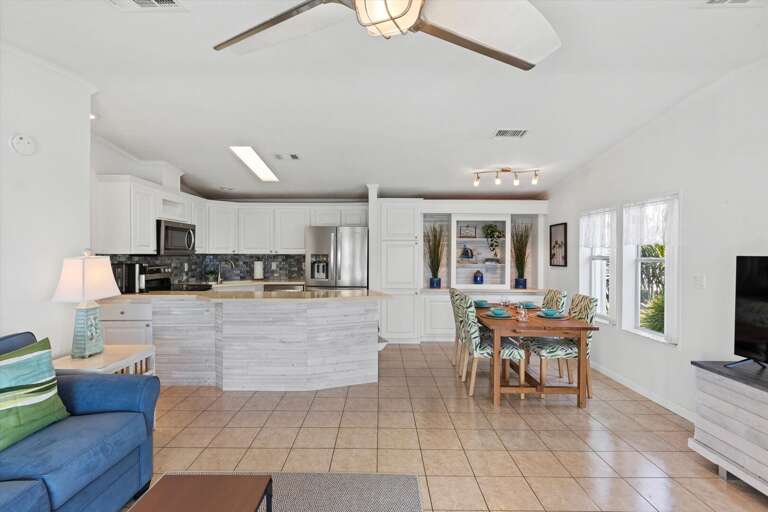 Spacious White Kitchen Blending Into Bright Blue Living Space