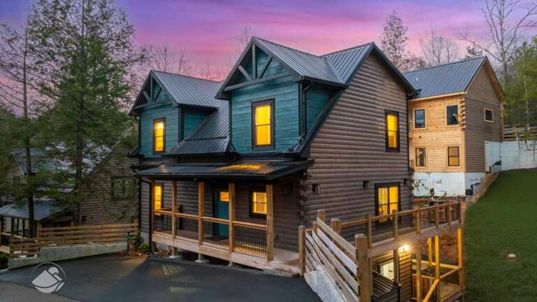Wood-clad Vacation Rental Under Twilight, With Illuminated Windows And Deck
