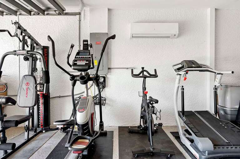 Gym Set Up in Garage with Peloton Bike, Treadmill, Elliptic Machine and AC