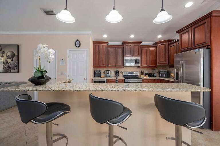 Kitchen With Bar Open to Living Room and Seating for Three