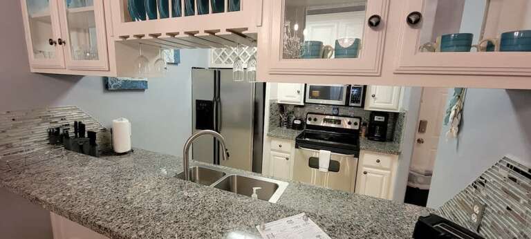 Vacation Rental Kitchen With Pale Pink Cabinets And Speckled Counters