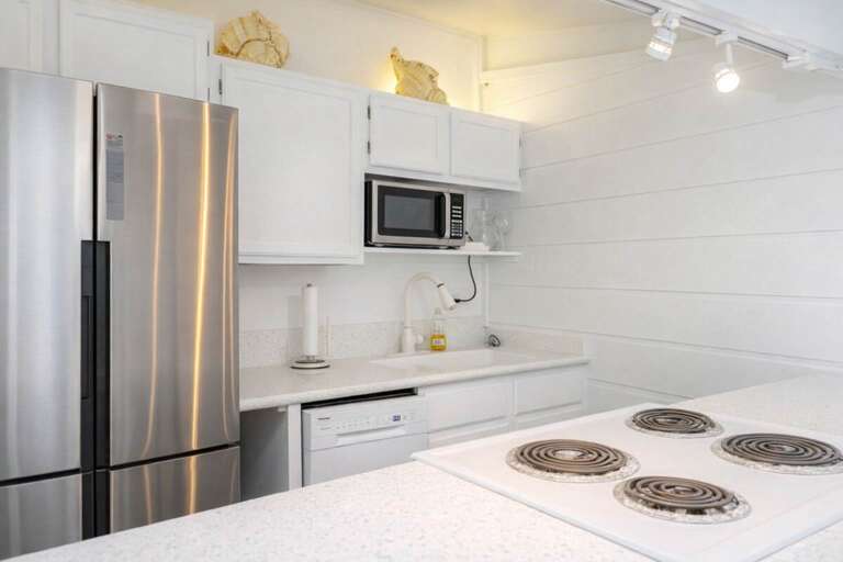 Sleek Kitchen With Stainless Fridge, Stovetop, And White Cabinetry