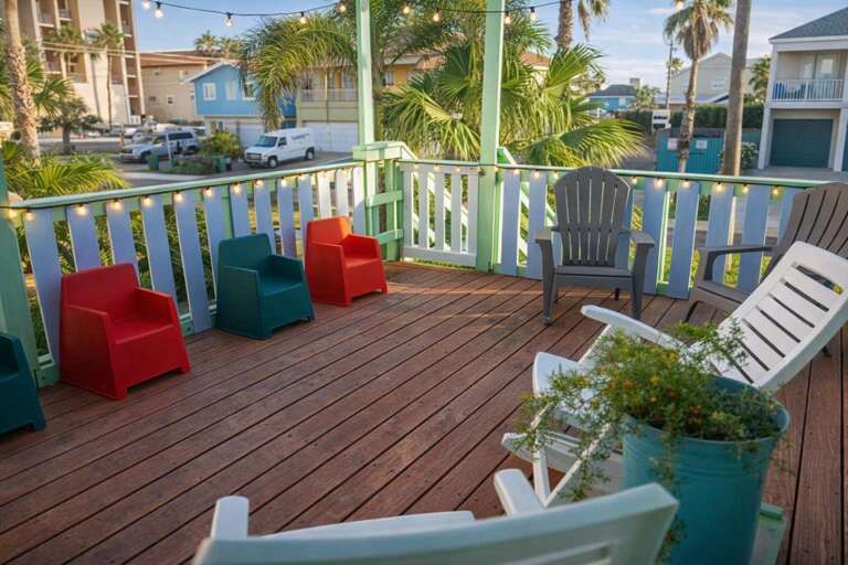Porch With Colorful Chairs, Potted Plants, String Lights, And Palm View