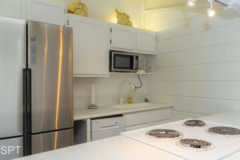 White-walled Kitchen With Stainless Steel Refrigerator And Stove In A Vacation Rental