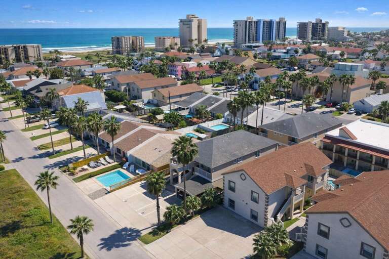 Coastal Community With Palm Trees And Pools Near The Ocean