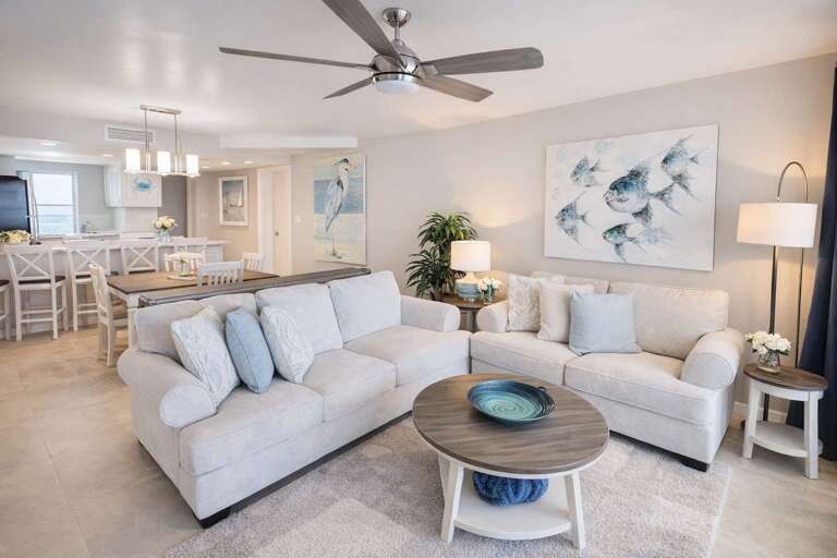 Living Room With Light Sofas, Circular Tables, Ceiling Fan, And Wall Art