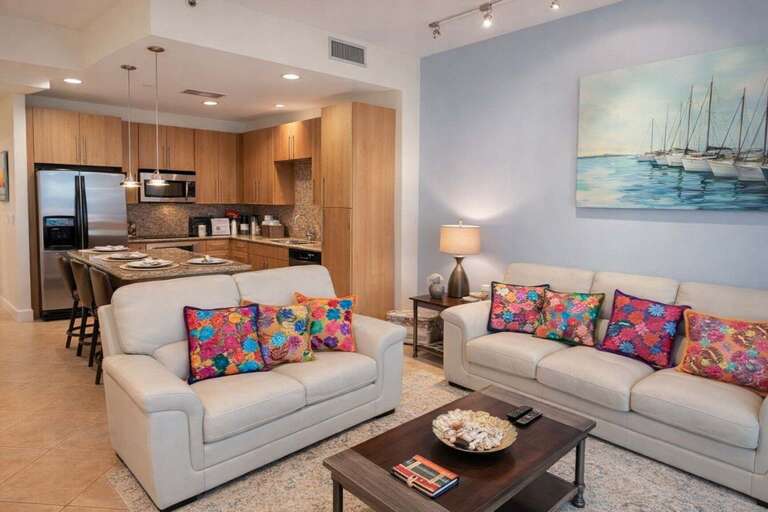 Open-plan Living Area With Kitchen, Sofas, Colorful Cushions, And Boat Painting