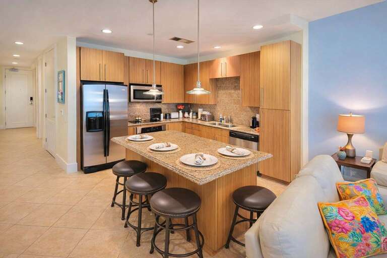Kitchen With Wooden Cabinets, Island, Stools, And Stainless Appliances