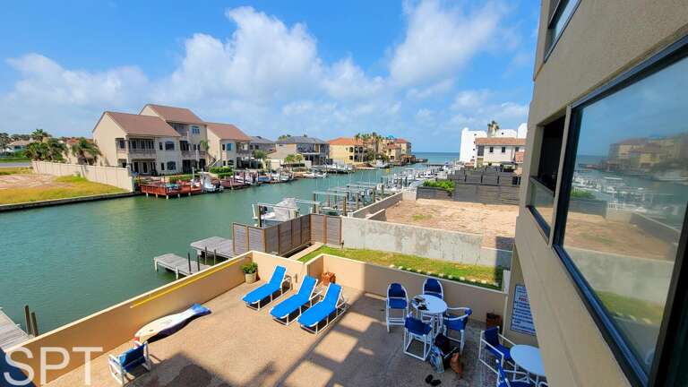 Balcony View Of Bright Blue Chairs And Canal, Buildings Beside Reflective Water