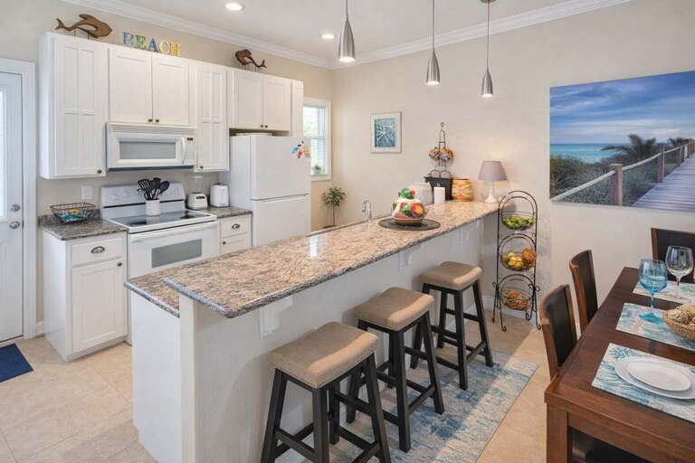 Kitchen With Counter, Stools, Dining Table, And Beach-themed Decor