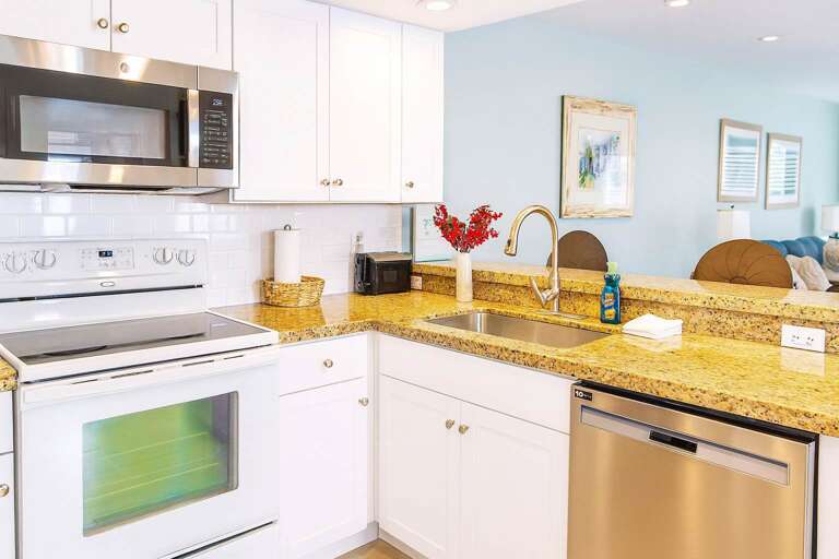 Bright Kitchen With Granite Countertops, Stainless Appliances, And Light Blue Wall