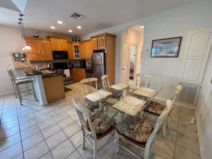 Spacious Kitchen With Dining Table, Tile Floors, And Wooden Cabinets