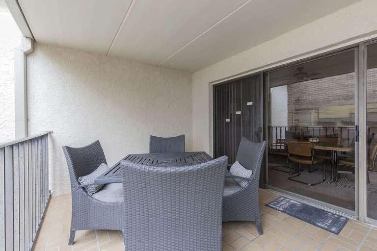 Balcony Scene With Wicker Seating, Sliding Doors To Dining Area Inside