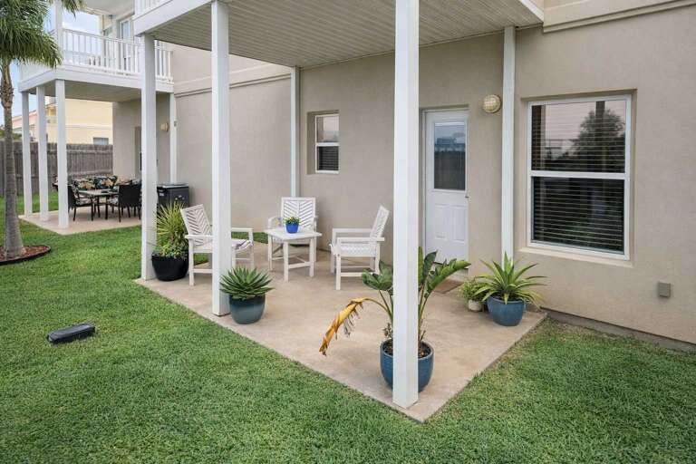 Patio With Potted Plants, Chairs, And Green Grass