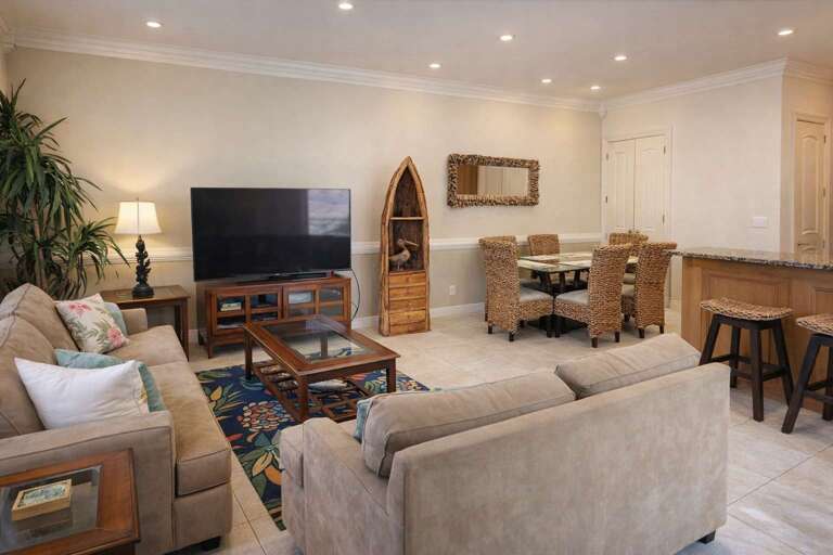 Living Room With Sofas, TV, Dining Area, And Bar Stools