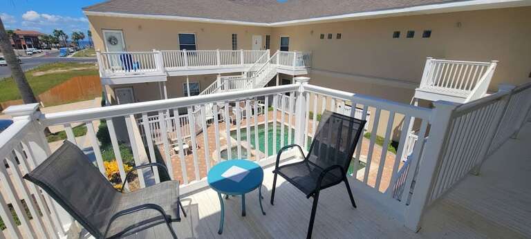Vacation Rental Balcony Overlooking Pool, Pristine Patio Chairs, And Vibrant Vistas