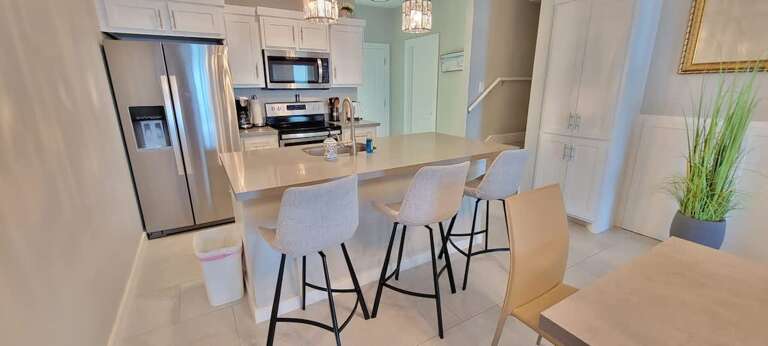 Spacious Kitchen And Dining Area In A Vacation Rental With Sleek Surfaces And Bar Stools