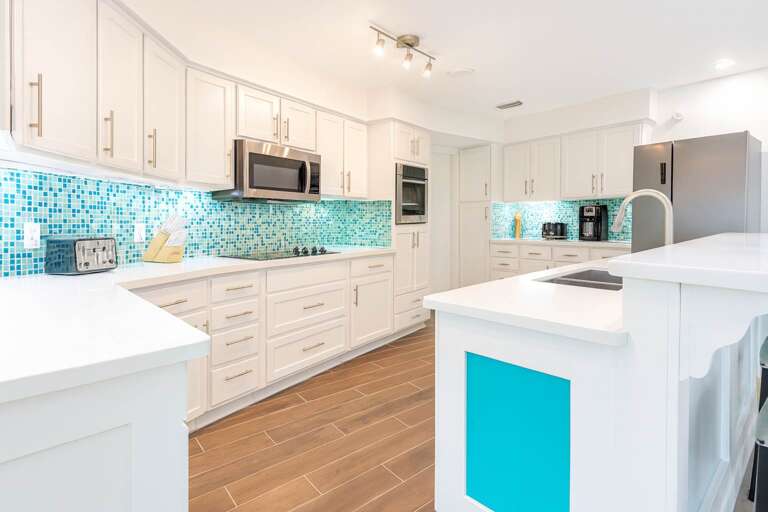 Bright Kitchen With White Cabinets, Turquoise Tiles, And Wood Floor