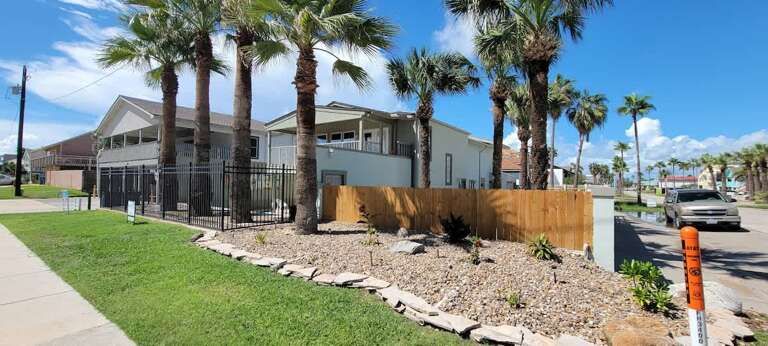 Palm-lined Pathway Leading To Gated Vacation Rental Under Sunny Skies