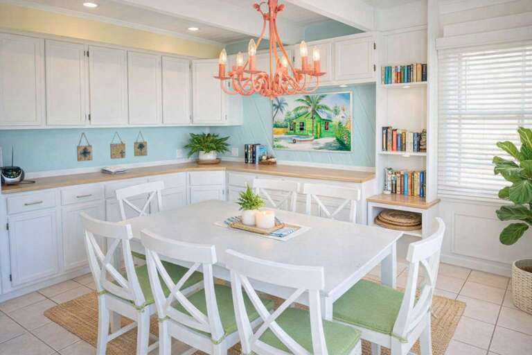 White Kitchen With Table, Tropical Artwork, And Coral Chandelier