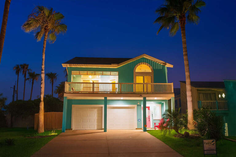Two-story Teal House With Tall Palm Trees At Twilight