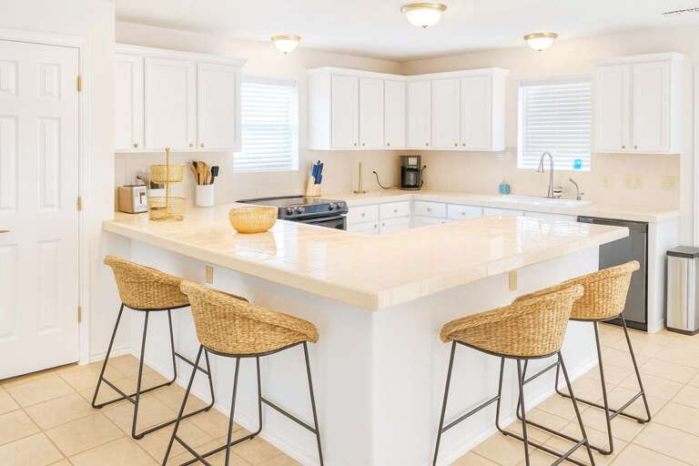 Spacious Kitchen With A Central Island And Wicker Stools