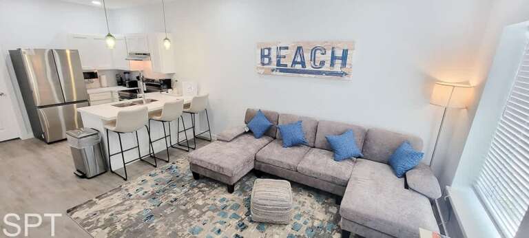 Bright Beach-themed Living Space With Sectional Sofa And Sleek Kitchen