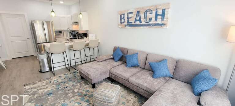 Living Room With Beach-themed Decor In Vacation Rental, Featuring Beige Sofa And Blue Cushions