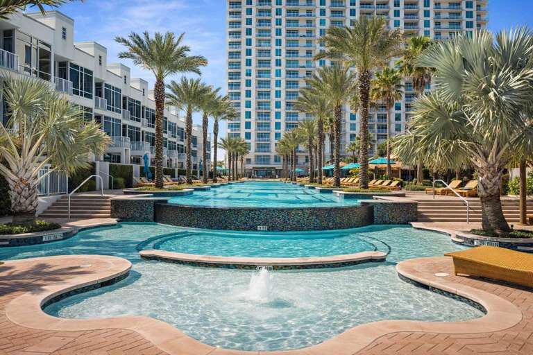 Palm-lined Pool With Cascading Water And Surrounding Loungers