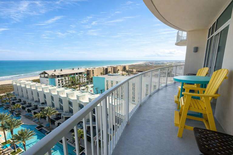 Balcony View With Ocean, Buildings, And Colorful Chairs
