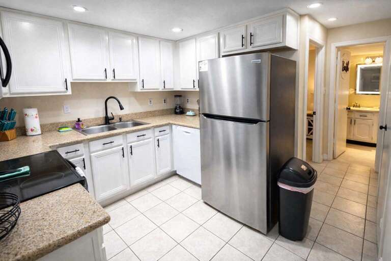 Spacious Kitchen With Stainless Steel Fridge And White Cabinets