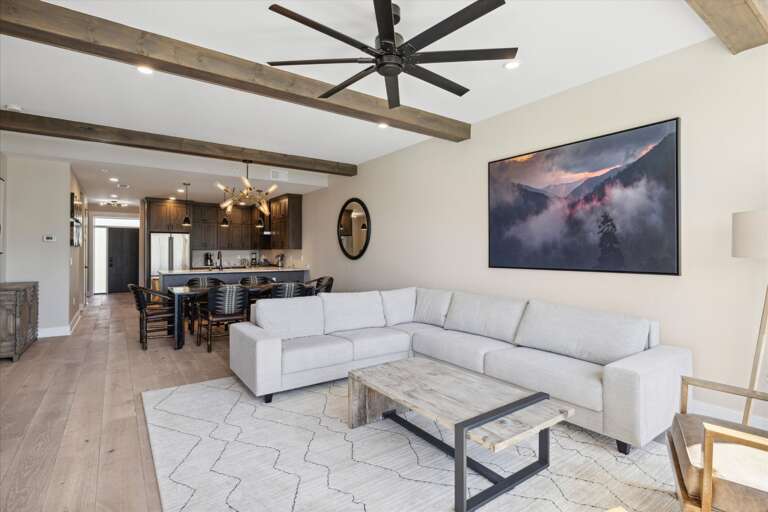 Spacious Living Space With Sectional Sofa And Ceiling Fan, Leading To A Dining Area