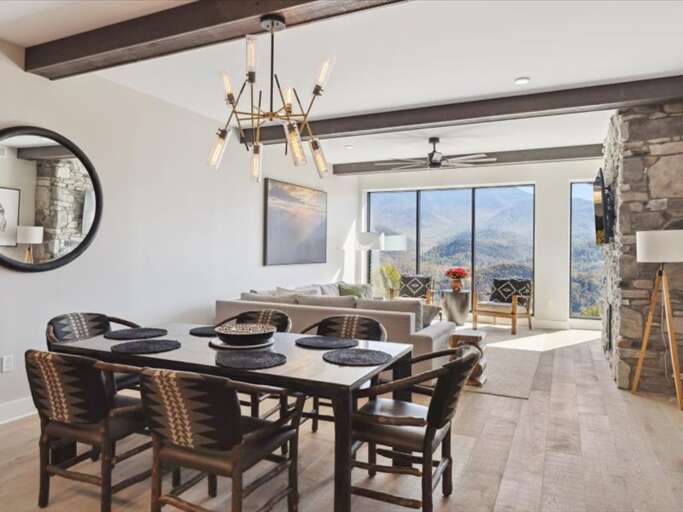 Dining Space In Vacation Rental With Mountain View, Stone Fireplace, And Chandelier