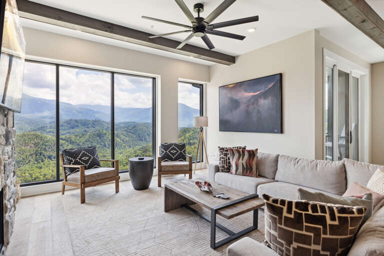 Living Room With Lush Landscape View Through Large Windows, Contemporary Furniture, And Ceiling Fan