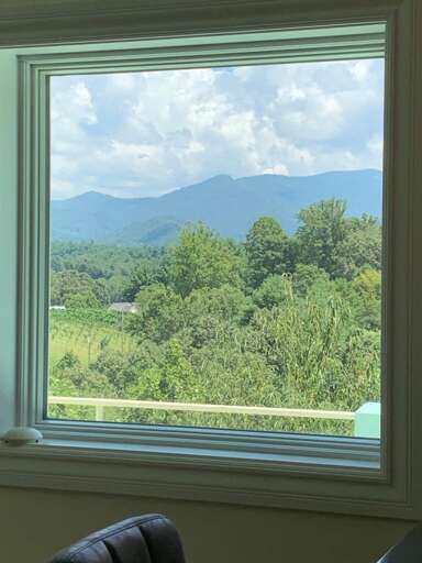 View From Vacation Rental Window Showing Lush Landscape And Distant Mountains