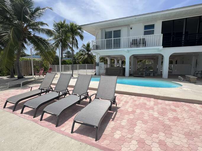 Spacious patio featuring a pool, hot tub, and comfortable lounge chairs