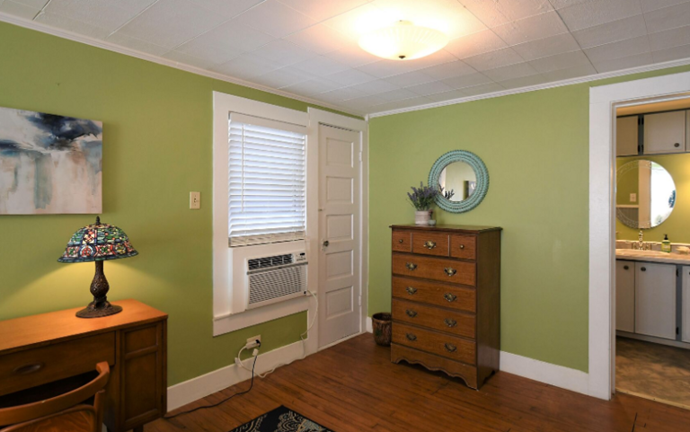 Bedroom on second floor, looking into bathroom area.  Desk, lamp and chair.