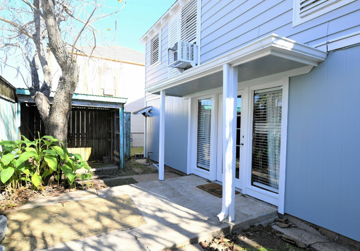 Back porch area, outside downstairs living area.  Picnic table in backyard, chairs and grill in front