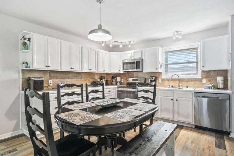 Enjoy cooking in this bright, modern kitchen featuring stainless steel appliances, plenty of counter space, and a comfortable dining table for gathering with family and friends.