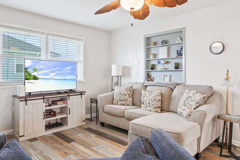 Light-filled living room with comfortable seating, coastal touches, and a TV for relaxing evenings.