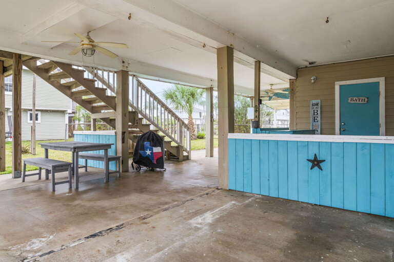 Relax in the shaded outdoor space featuring a picnic table, grill, and convenient beach rinse area.
