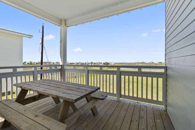 Private covered balcony with picnic table, perfect for enjoying fresh coastal air and relaxing views.