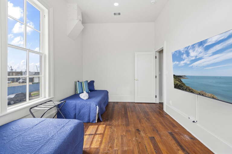 Bright, airy bedroom with large windows, simple comforts, and a peaceful, relaxed vibe.