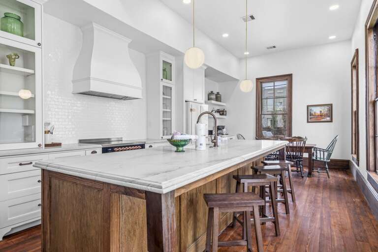 Bright, chef-style kitchen with a spacious marble island, custom cabinetry, and inviting dining space for gathering.