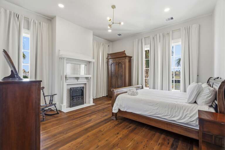 Serene, light-filled bedroom with elegant wood furnishings, a cozy fireplace, and timeless charm.