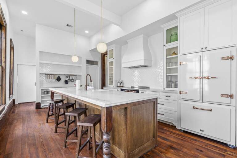 Stunning chef's kitchen with a large marble island, custom cabinetry, and designer finishes, perfect for gathering and entertaining.
